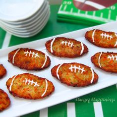 some crab cakes are on a plate with white frosting and football shaped cookies in the middle