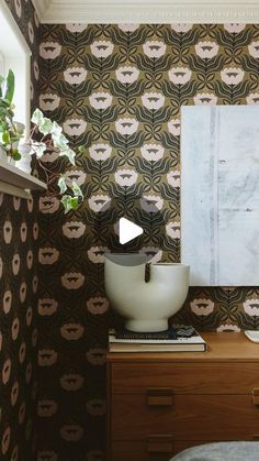 a room with wallpaper and a painting on the wall next to a dresser in front of a window