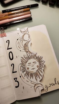 an open notebook with the sun and moon on it, next to some crayons