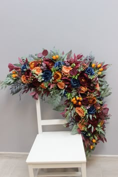 a white chair sitting next to a flower covered arch on top of a wooden floor