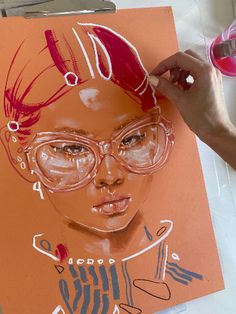 a drawing of a woman with glasses on an orange sheet of paper next to some scissors