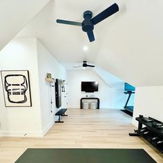 a room with a ceiling fan and exercise mats on the floor in front of it