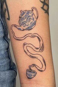 a woman's arm with tattoos on it, including a teapot and two cups