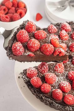 chocolate cake with raspberries and powdered sugar on top, cut in half