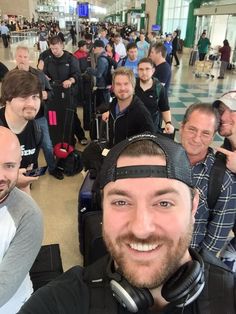 a group of people standing around each other in an airport with luggage and headphones on