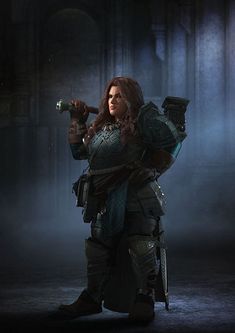 a woman dressed in armor and holding a hammer stands in a dark, foggy room