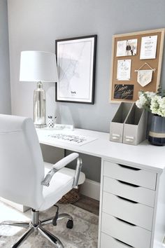 a white chair sitting in front of a desk with a lamp and pictures on the wall