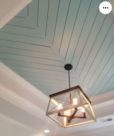 a chandelier hanging from the ceiling in a room with white walls and wood paneling