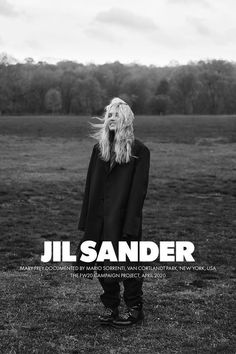 a woman standing in a field with her hair blowing in the wind and text reading jil sander