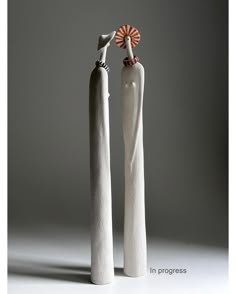 two tall white vases sitting next to each other in front of a gray background