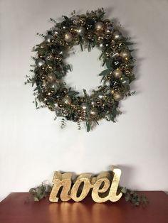 a christmas wreath on top of a wooden table next to a sign that says noel