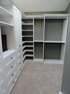 an empty walk in closet with white shelves and gray doors, carpeted flooring