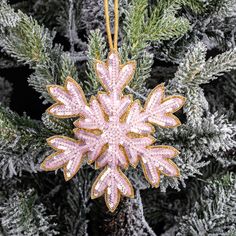 a pink snowflake ornament hanging from a tree