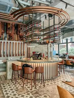 a bar with lots of bottles hanging from the ceiling and stools at one end