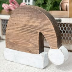 a wooden object sitting on top of a white rug next to a potted plant