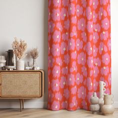 an orange and pink shower curtain next to a wooden cabinet with vases on it