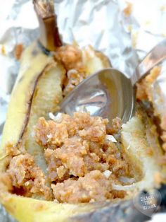 a close up of a banana split in half on tin foil with a spoon sticking out of it