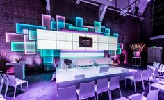 a room filled with lots of white chairs next to a wall covered in neon lights