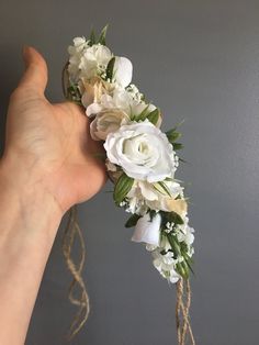 a hand holding a bouquet of flowers on top of a string tied to the wall