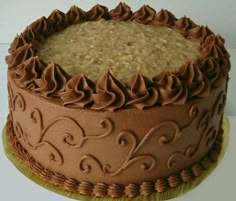 a chocolate cake with frosting and swirls on top sitting on a gold plate