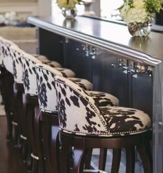 a row of bar stools sitting in front of a counter with flowers on it