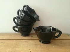 four black cups sitting on top of a wooden table