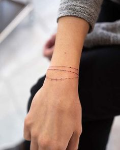 a woman's wrist with a thin line tattoo on it