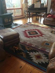 a living room filled with furniture and a large rug on the floor in front of a window