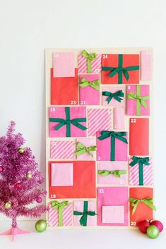 a pink and green christmas tree sitting in front of a calendar with presents on it