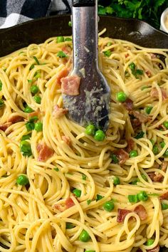 pasta with peas and bacon in a skillet being stirred with a spatula to stir it