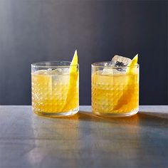 two glasses filled with lemonade on top of a table