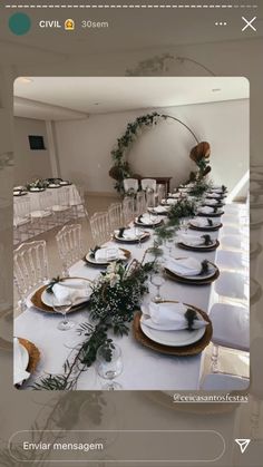 the table is set with white plates and greenery on it for an elegant dinner