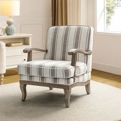 a striped chair sitting on top of a rug in front of a white dresser and window