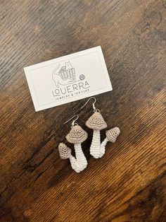 two small crocheted mushrooms are sitting on a table next to a business card