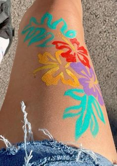 someone has painted their legs with colorful flowers and leaves on the side of their body