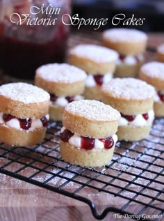 mini victoria sponge cakes on a cooling rack with powdered sugar and jelly toppings