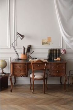 an antique desk with two chairs and a lamp