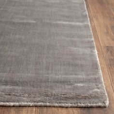 a gray rug on top of a wooden floor