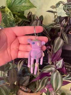 a person is holding a small toy in front of some plants and potted plants