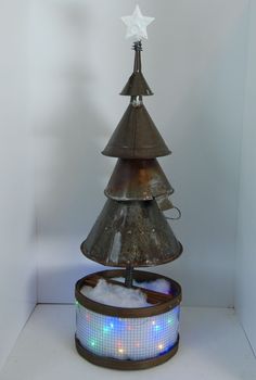 a christmas tree made out of an old tin can with lights on it and a star hanging from the top