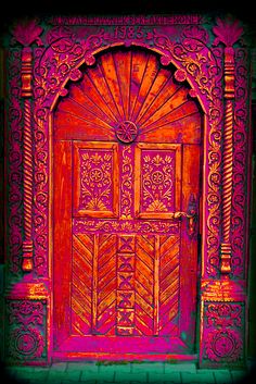 an ornate wooden door with pink paint on it