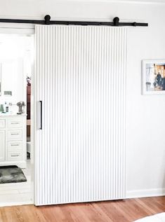 an open sliding door in a white room with hardwood floors and walls, along with a rug on the floor