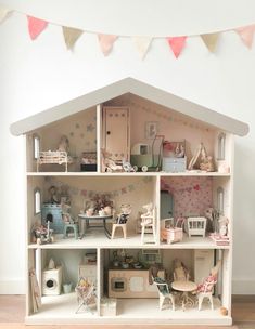 a doll house with lots of furniture and accessories on it's shelves in front of a white wall