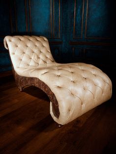 an antique chaise lounge chair in a dark room with blue walls and wood flooring