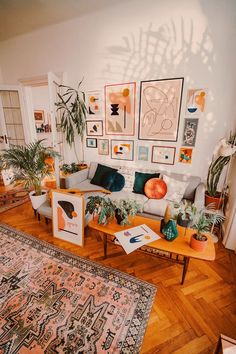 a living room filled with lots of furniture and plants on top of a wooden floor