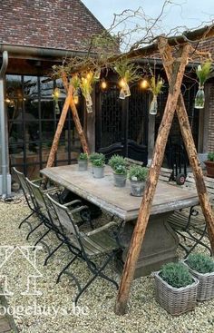 an outdoor dining area with potted plants and lights hanging from the roof over it