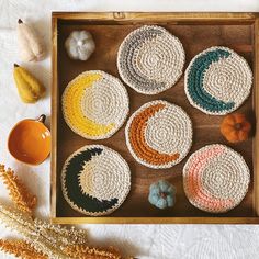 crocheted coasters are arranged on a tray next to pumpkins and gourds