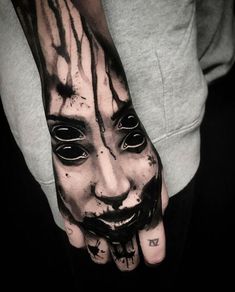 a man's hand with a creepy face painted on it and black ink splatters