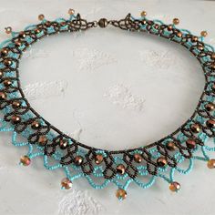 a blue and brown necklace with beads on it's neckline, sitting on a white surface