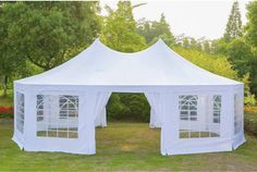 a large white tent sitting on top of a lush green field next to trees and bushes